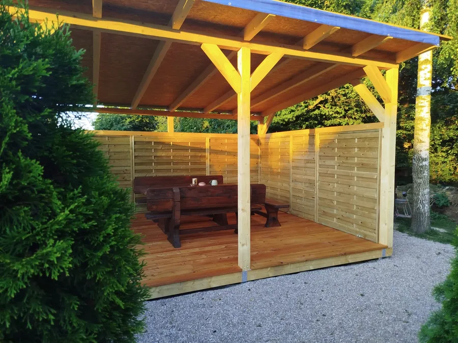 Nová krytá pergola s dřevěným stolem a lavicemi pro hosty